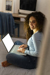 Young woman with laptop in bedroom at home - GIOF14628