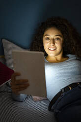 Junge Frau mit Tablet-PC auf dem Bett liegend zu Hause - GIOF14636