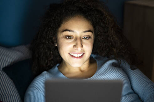 Smiling young woman using tablet PC in bedroom - GIOF14637