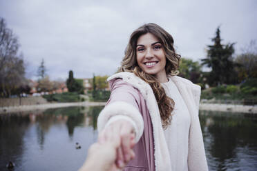 Lächelnde Frau hält die Hand ihres Freundes am Seeufer - EBBF05116