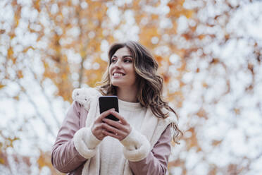 Lächelnde Frau mit Mobiltelefon im Park - EBBF05121