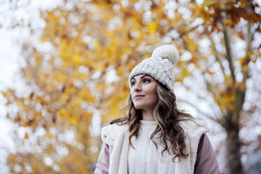 Thoughtful woman wearing knit hat at autumn park - EBBF05124