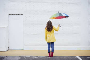 Frau hält bunten Regenschirm auf dem Fußweg - EBBF05154