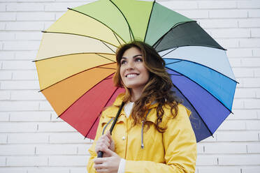 Nachdenkliche Frau mit Regenschirm vor einer Mauer - EBBF05159