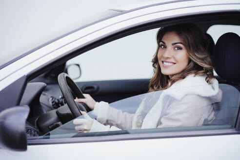 Lächelnde junge Frau, die Auto fährt und aus dem Fenster schaut - EBBF05187