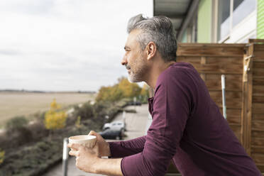 Mann hält Kaffeetasse auf Balkon - JCCMF04878