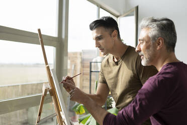 Gay couple painting on canvas at home - JCCMF04885