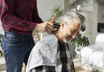 Ehemann schneidet die Haare seines Mannes mit einem elektrischen Rasiermesser zu Hause - JCCMF04907