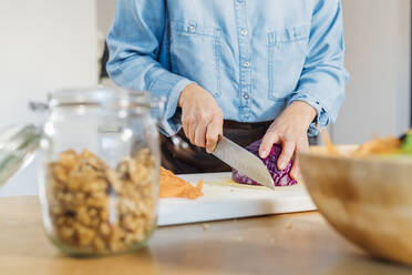 Woman cutting red cabbage on cutting board at home - MEUF05122