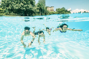 Eltern schwimmen mit Kindern im Schwimmbad an einem sonnigen Tag - WFF00542