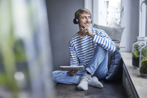 Lächelnder arbeitender Mann mit Tablet-PC auf dem Sofa zu Hause - FMKF07384