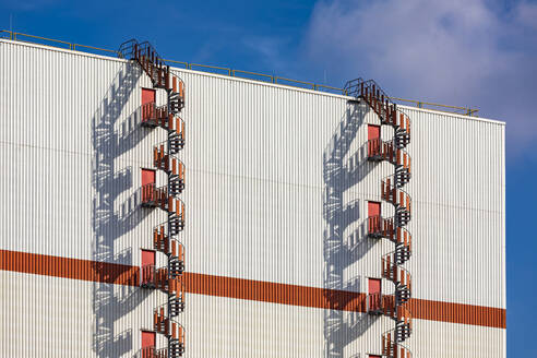 Deutschland, Bremen, Ein Paar spiralförmige Feuerleitern vor einer Industriehalle - WDF06716