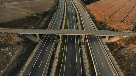 Leere Brücke über eine Autobahn, die an einem landwirtschaftlichen Feld in Lleida, Spanien, vorbeiführt - ACPF01420