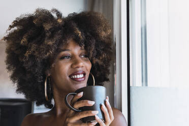 Lächelnde Frau trinkt Kaffee zu Hause - PNAF02682