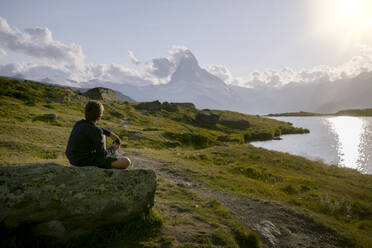 Wanderer sitzt auf einem Felsen und schaut auf das Matterhorn, Zermatt, Schweiz - LOMF01297