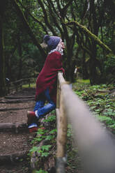 Thoughtful woman leaning on railing in forest - SIPF02699