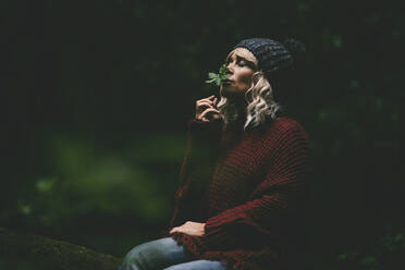 Frau riecht an grünem Blatt im Wald - SIPF02718