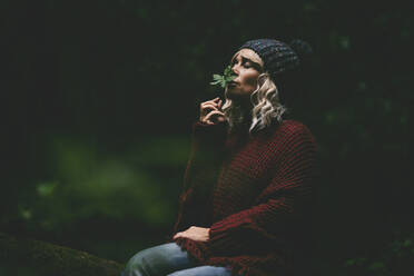 Woman smelling green leaf in forest - SIPF02718