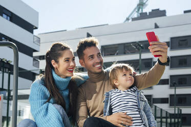 Lächelnder Vater nimmt Selfie mit Familie auf Smartphone - PGF00966