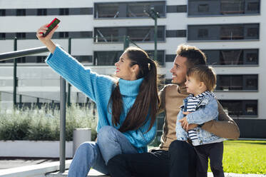 Frau macht Selfie mit Familie auf Handy in der Stadt - PGF00967