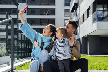 Fröhliche Mutter nimmt Selfie mit Familie auf Smartphone in der Stadt - PGF00968