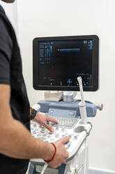 Doctor using keyboard on medical equipment in hospital - DLTSF02522