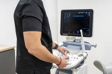 Gynecologist working on medical scanner at clinic - DLTSF02523