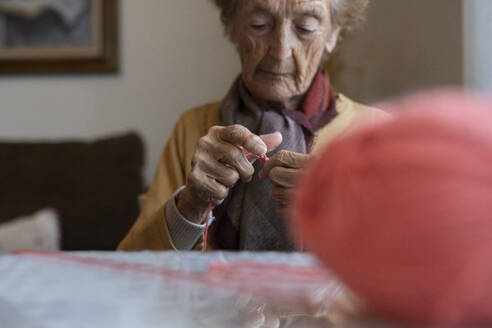 Ältere Frau im Ruhestand strickt am Tisch - JCCMF04929