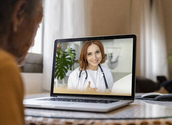 Senior woman on video call with doctor through laptop at home - JCCMF04934