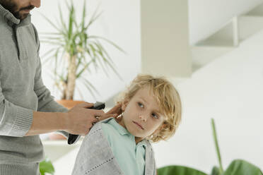 Father cutting son's hair with electric razor at home - JCCMF04943