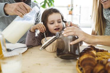 Cute girl having breakfast with parents at home - JCCMF04961