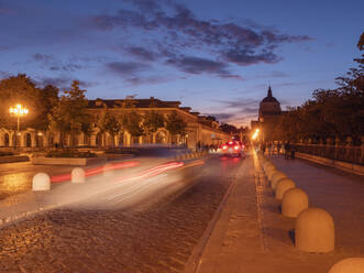 Spanien, Madrid, Aranjuez, Unscharfe Bewegung von Autos auf einer Kopfsteinpflasterstraße in der Abenddämmerung - LAF02727