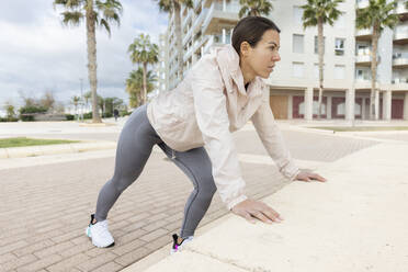 Dedicated woman exercising on concrete - JPTF01011