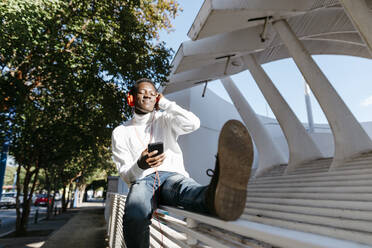 Man listening music with eyes closed on railing - TCEF02163