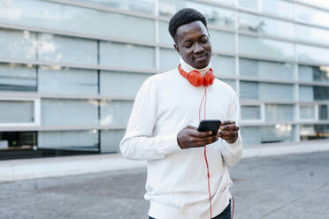 Mann mit Kopfhörern und Smartphone auf dem Gehweg - TCEF02167