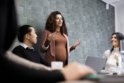 Pregnant businesswoman sharing business ideas with male and female colleagues during meeting - MASF27979