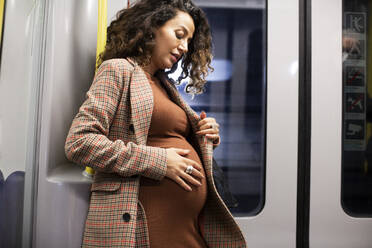 Schwangere Geschäftsfrau berührt Unterleib während der Fahrt im Zug - MASF28020