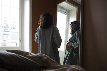 Schwangere Frau schaut in den Spiegel im Schlafzimmer - MASF28037