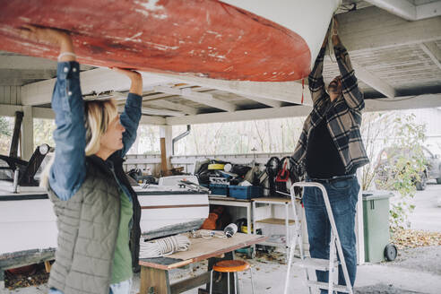 Mature man tying nautical vessel while female friend helping him in garage - MASF28129