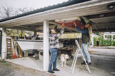 Heterosexual couple tying nautical vessel in garage - MASF28130