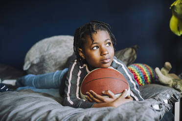 Girl looking away while contemplating in bedroom at home - MASF28145