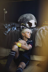 Trauriger Junge mit Fußball, der im Schlafzimmer wegschaut - MASF28169