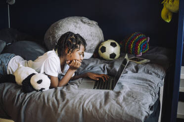 Ambitious girl learning coding on laptop in bedroom - MASF28213