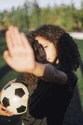 Girl shielding eyes from sunlight on sports field - MASF28230