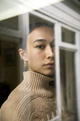 Porträt einer jungen Frau, die sich im Fenster spiegelt - ISF25518