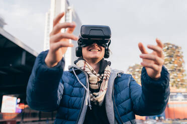 Italien, Lächelnder Mann mit VR-Brille in der Stadt - ISF25537