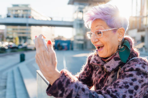 Italien, Lächelnde modische ältere Frau mit Smartphone in der Stadt - ISF25547