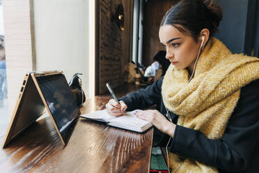 Konzentriertes Mädchen beim E-Learning mit Laptop im Café - JRVF02356