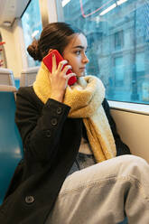 Teenager, der durch das Fenster schaut und im Bus mit seinem Handy telefoniert - JRVF02361