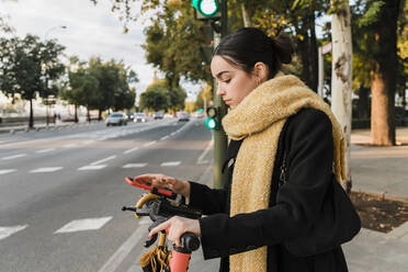 Teenager using smart phone on electric push scooter in city - JRVF02364